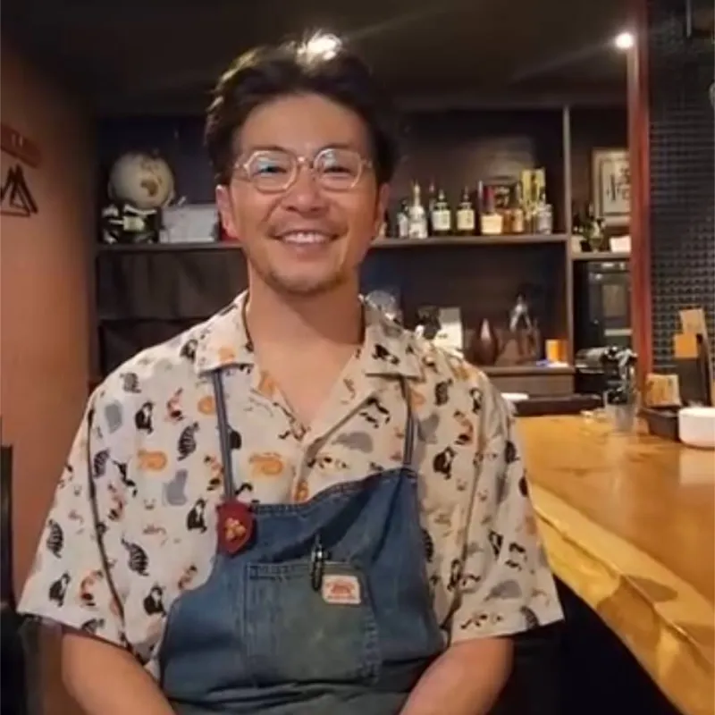 カウンター越しに笑顔を見せるワインバーのオーナー様